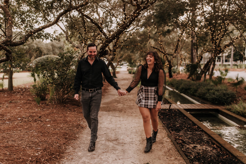 couple walking holding hands happily together on a woodsy trail in Watercolor Beach, Florida
